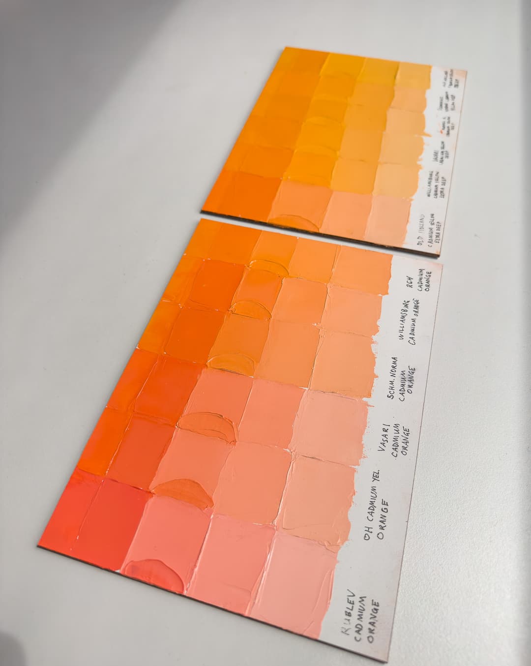 Artist paint colors in orange and yellow displaying the variety of hues for the pigments PO20 and PY35 in oil paint. Two panels have swatches of paint from different brands.