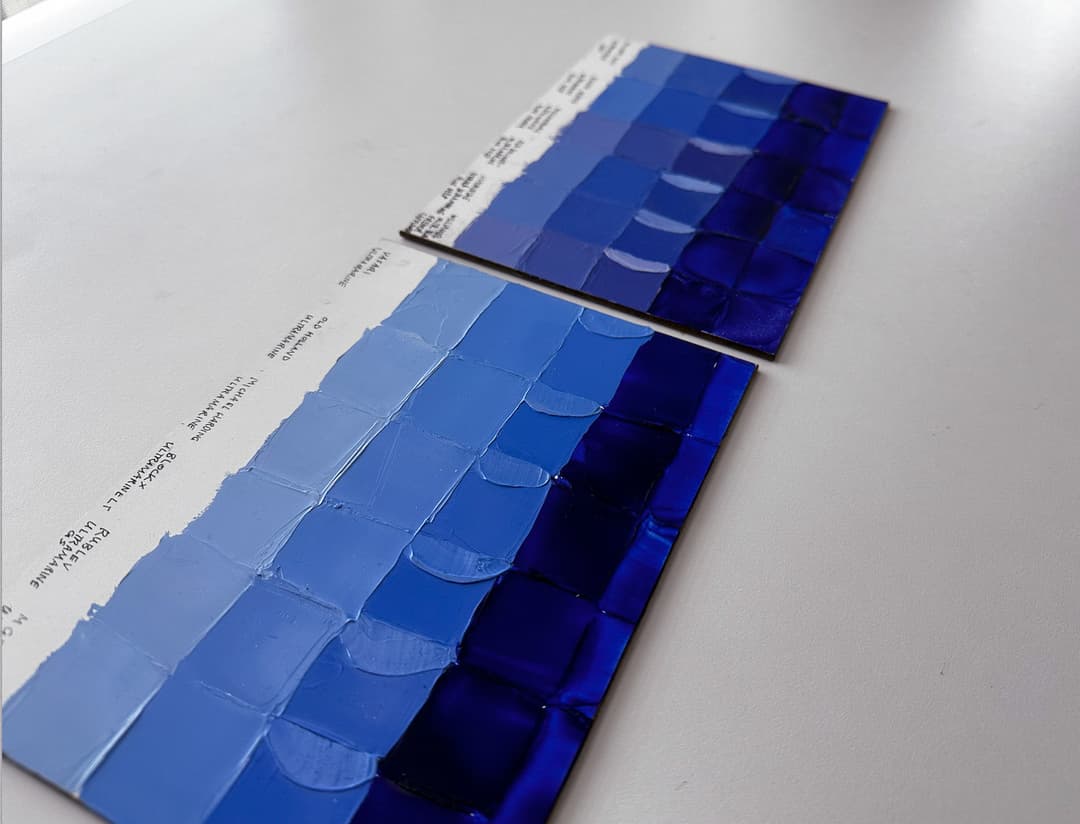 Two panels showing swatches of different brands of oil paint. The closer panel shows Ultramarine Blue, more of a middle blue, while the far panel contains different versions of Ultramarine Blue Deep, which is more purple.