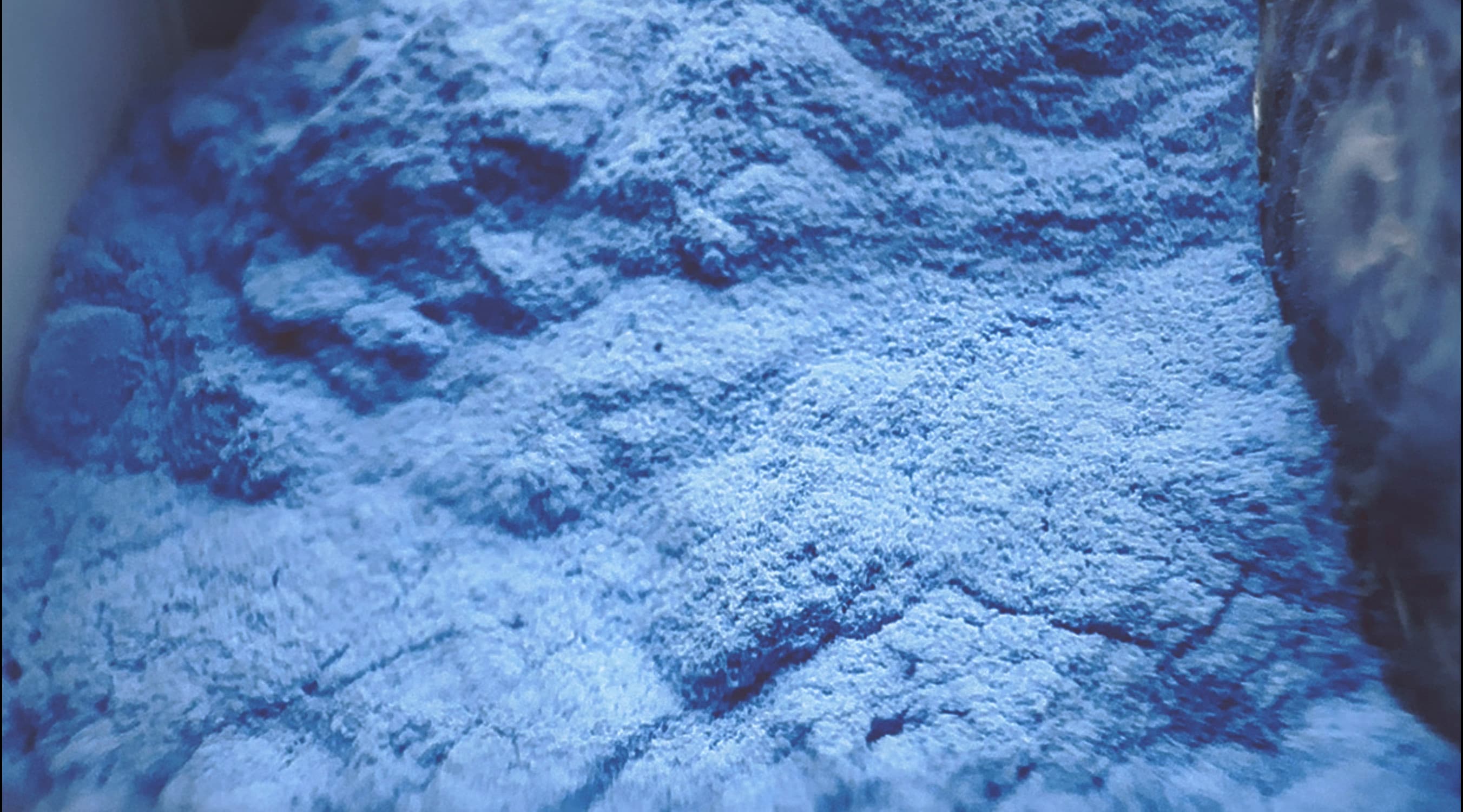 Grainy blue pigment in a plastic jar