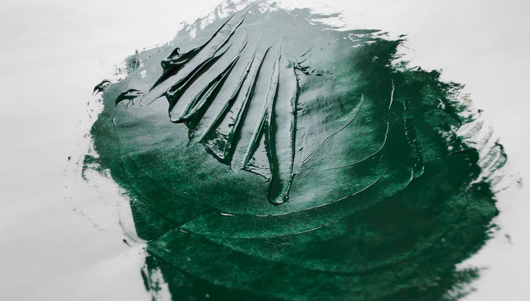 Impasto paint strokes made by a palette knife through green oil paint