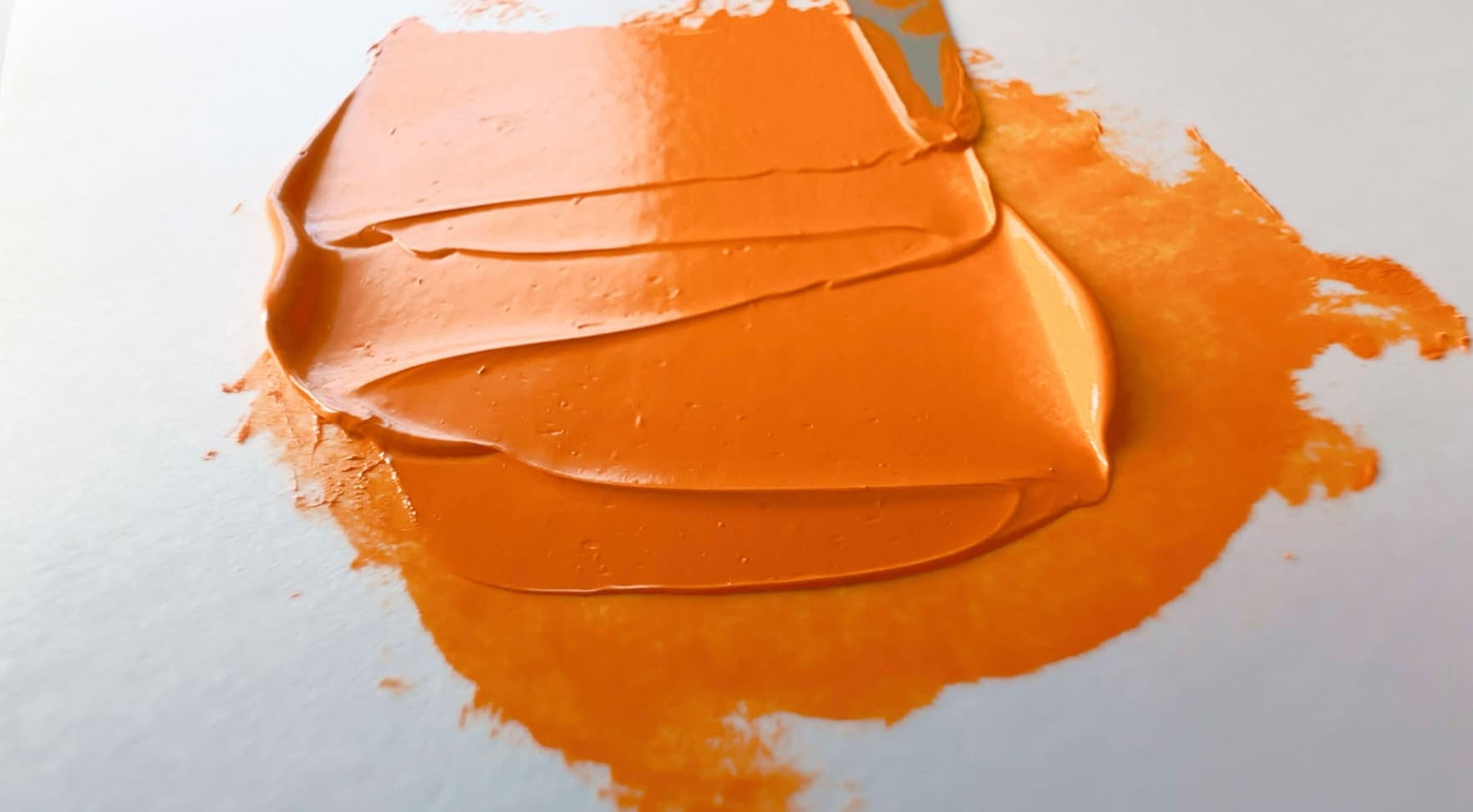 A bit of orange oil paint pulled back and forth by a palette knife