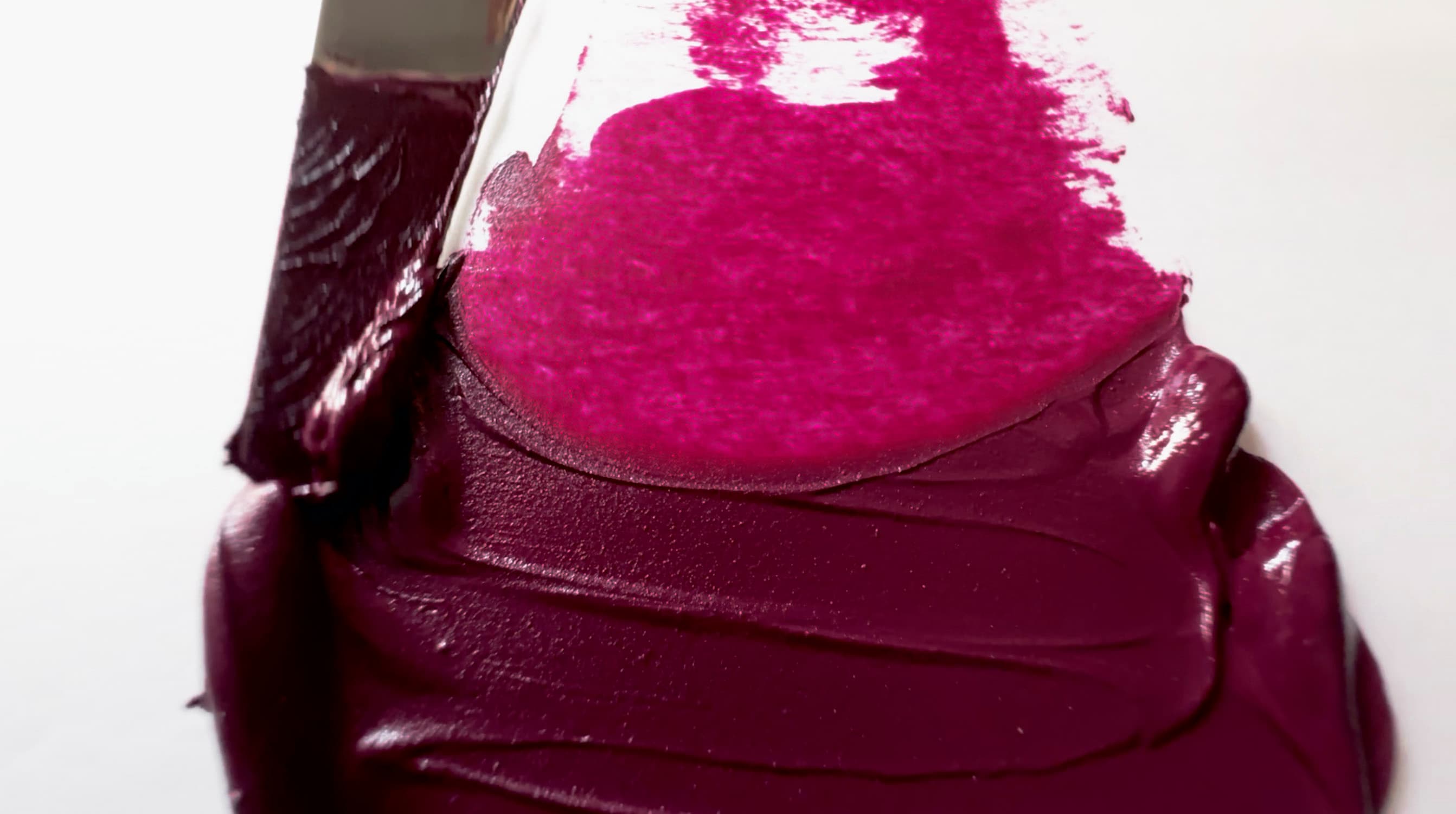 A swoosh of Quinacridone Magenta oil paint is cut away to show how chromatic even a tiny residue of the paint can be