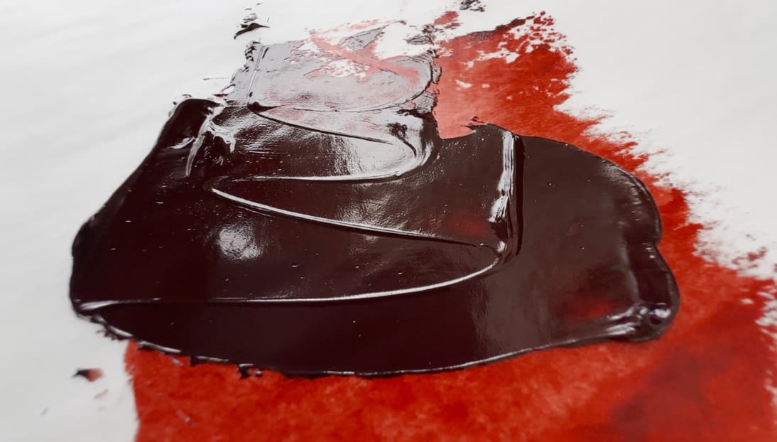 Deep brown swoosh of oil paint. Where the paint is thin the color is a vibrant red orange