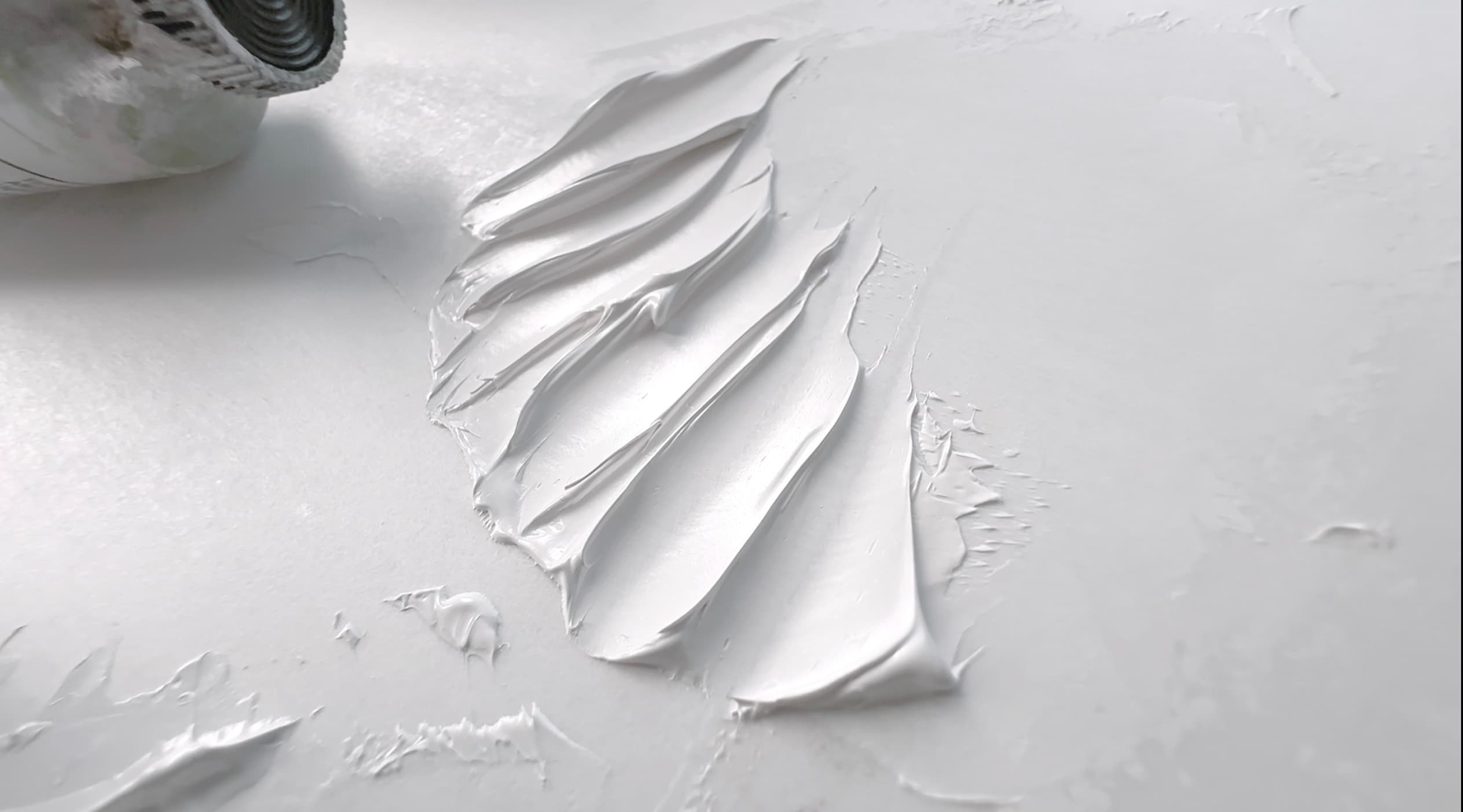 An impasto swatch of Gamblin Titanium White with stiff-edged troughs made with a palette knife. The texture is very smooth, almost plastic-smooth in its surface finish